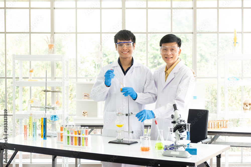 Science, Chemistry, Technology, Biology and Laboratory concept - Portrait of Asian senior and junior scientists are pleased their experimental results in a test glass beaker. Science, Chemistry, Technology, Biology and Laboratory concept - Portrait of Asian senior and junior scientists are pleased their experimental results in a test glass beaker.