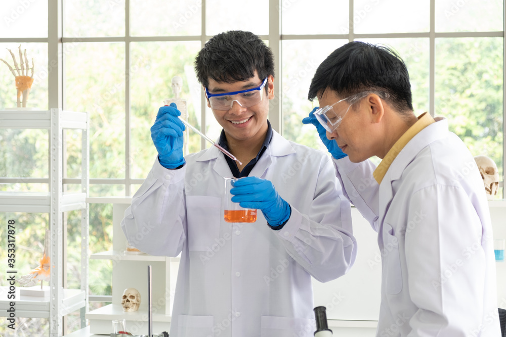 Science, Chemistry, Technology, Biology and Laboratory concept - Asian senior scientist is considering an experiment result in glass beaker of Asian junior scientist. Science, Chemistry, Technology, Biology and Laboratory concept - Asian senior scientist is considering an experiment result in glass beaker of Asian junior scientist.