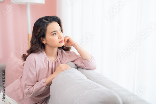 Close up young Asian woman upset when sitting at couch at home.