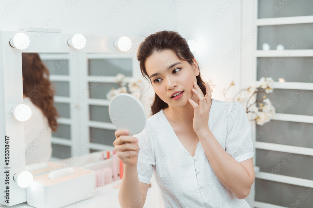 people and beauty concept - beautiful woman with mirror touching her face skin at home bedroom people and beauty concept - beautiful woman with mirror touching her face skin at home bedroom