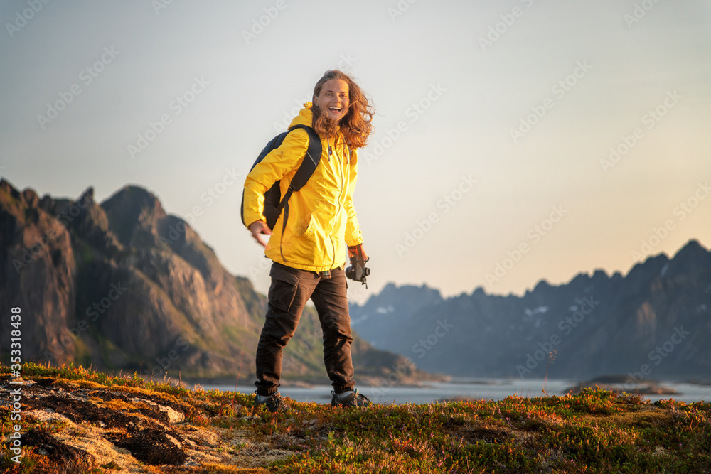 Tourist woman walking in Norway mountains vacations wearing yellow raincoat explore Lofoten islands