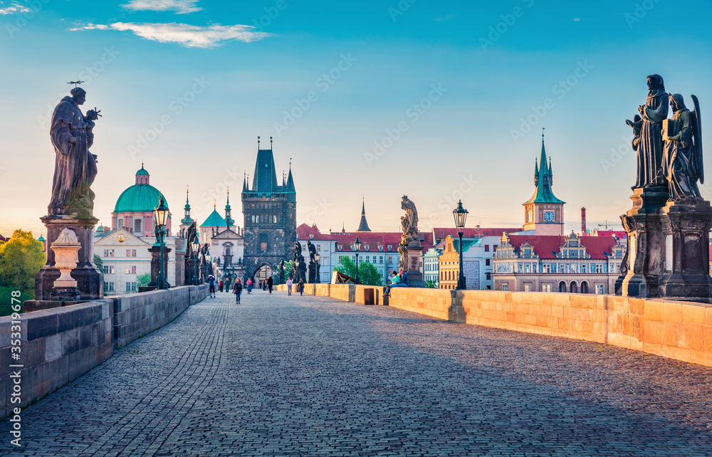 Obraz premium Romantic morning view of Charles bridge on Vltava river (Karluv Most) with statues and Saint Francis of Assisi Church. Colorful summer cityscape of Prague, Czech Republic, Europe.
