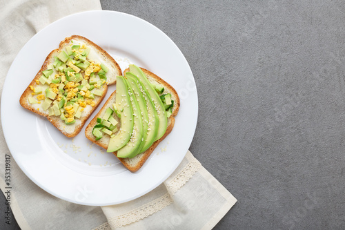 Avocado toast. Healthy toast with avocado and different toppings om white plate, copy space, top view.