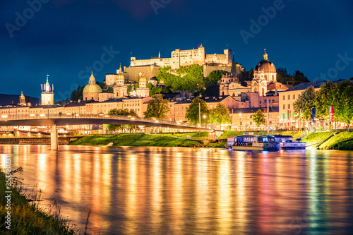 Old town of Salzburg reflected in the calm waters of Salzach river. Spectacular night cityscape of Salzburg with Hohensalzburg Castle on background. Austria, Europe. Traveling concept background.