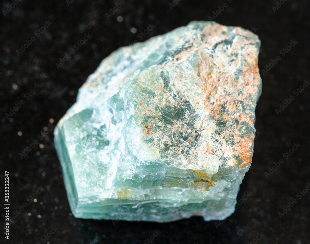 closeup of sample of natural mineral from geological collection - raw Apatite rock on black granite background closeup of sample of natural mineral from geological collection - raw Apatite rock on black granite background