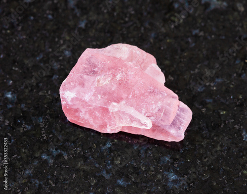 closeup of sample of natural mineral from geological collection - raw Rhodochrosite crystal on black granite background from Wutong mine, Liubao, Guangxi prov, China photo