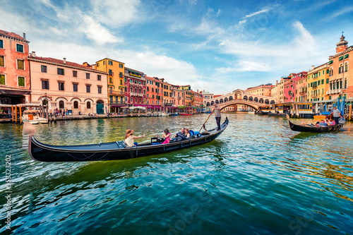 Romantic summer scene of famous Canal Grande. Stunning morning view of Rialto Bridge. Picturesque cityscape of Venice with tourist on gondolas, Italy, Europe. Traveling concept background.