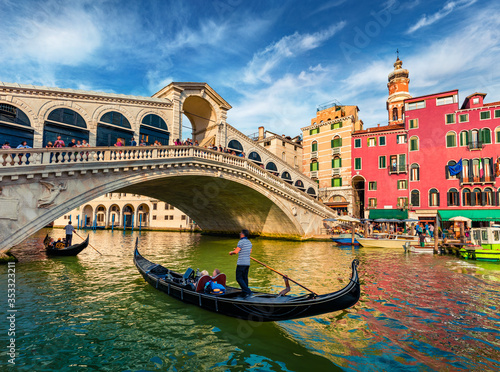 Colorful morning view of Rialto Bridge. Amazing cityscape of Venice with tourists on gondolas, Italy, Europe. Romantic summer scene of famous Canal Grande. Traveling concept background.