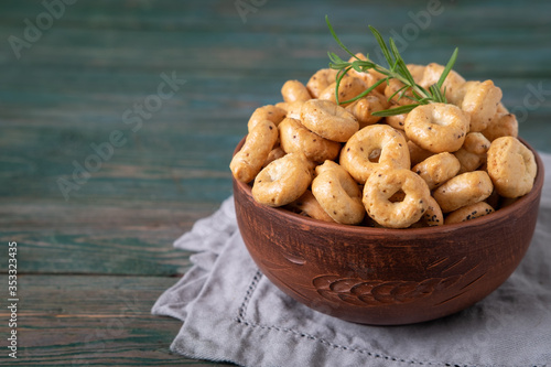 Traditional Italian snack tarallini, taralli in a ceramic bowl on a wooden background