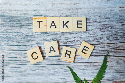 lettering take care is made of small wooden blocks printed on a wooden background with a green fresh leaf of greenery. medical ready-made modern content