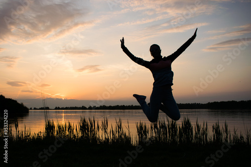 A young woman is jumping, sunset as background. Freedom and happiness concept photography,
