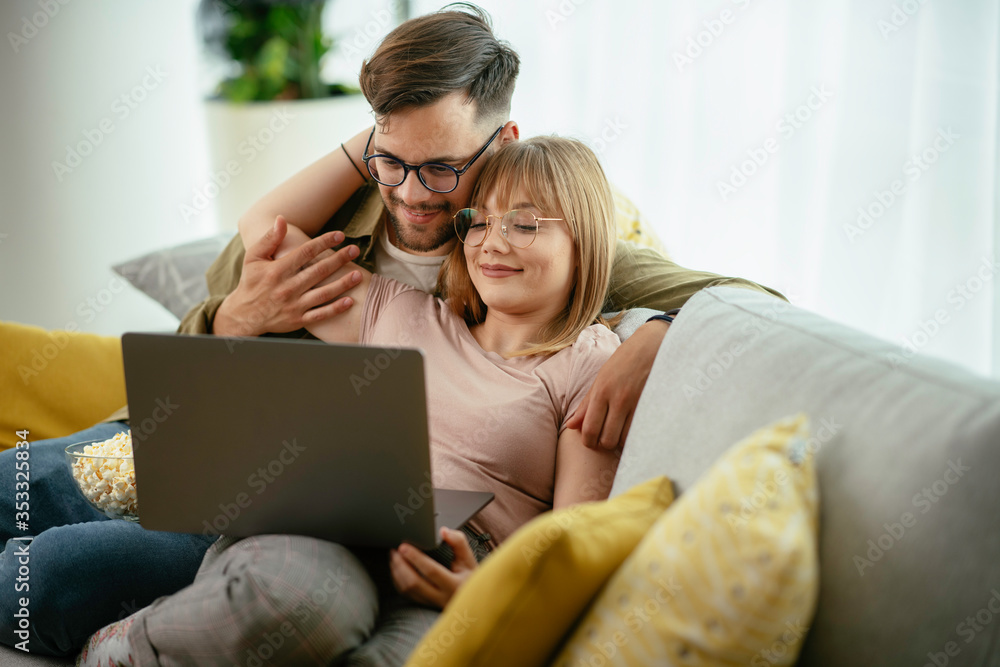 Young couple watching movie on lap top. Loving couple enjoying at home. Young couple watching movie on lap top. Loving couple enjoying at home.