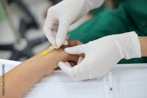 Nurses in green uniforms wear gloves, use syringes to pierce the patient's wrists.