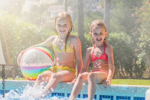 Two beautiful girls at swimming pool in summer time