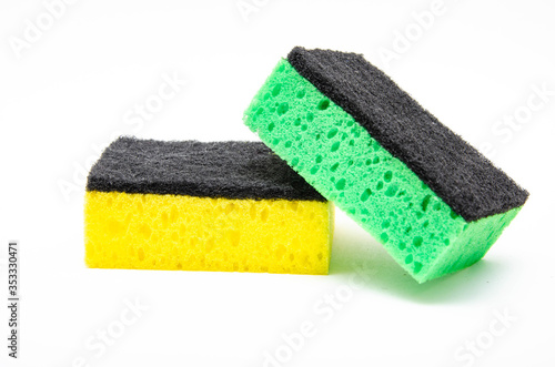 Sponge for washing dishes on a white background. Washcloth of green and yellow color. Two sponges are stacked on top of each other in macro. The green sponge hangs in half, lies sideways