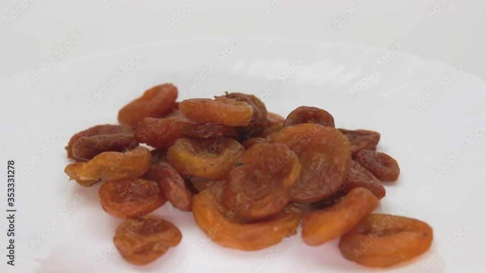 A pile of dried apricots rotates on a white background. A pile of dried apricots rotates on a white background.