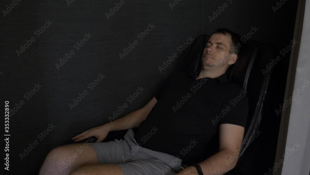 Young Man Lying, Relax and Enjoying in Black Massage Chair in the Lounge Area in Airport Young Man Lying, Relax and Enjoying in Black Massage Chair in the Lounge Area in Airport