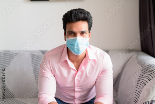 Young Indian businessman with mask for protection from corona virus outbreak staying at home under quarantine