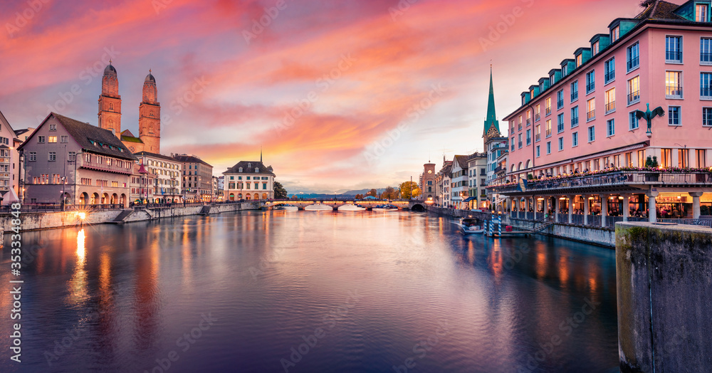 Dramatic evening view of Fraumunster and Grossmunster Churches. Illuminated autumn cityscape of Zurich, Switzerland, Europe. Sunset on Limmat River. Traveling concept background.