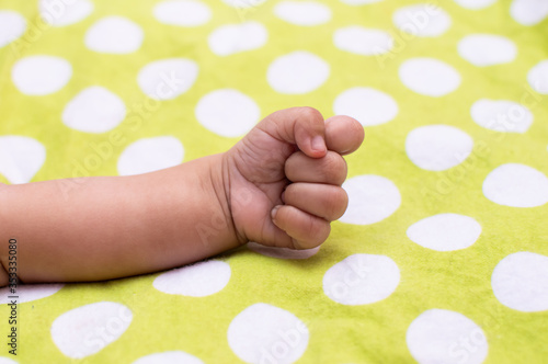 Closed fist of an infant on polka dots © Tejjas