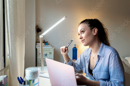 Young attractive female doing homework sitting desktop with modern laptop computer