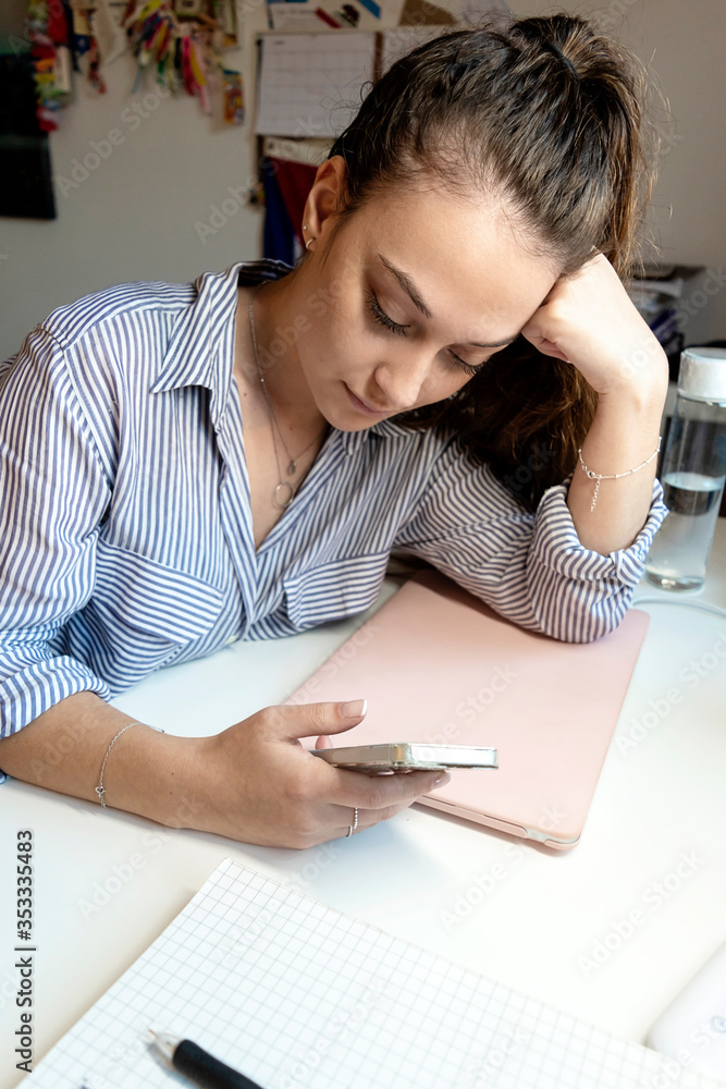 Young woman sitting at a laptop and using a smartphone. Young woman sitting at a laptop and using a smartphone.