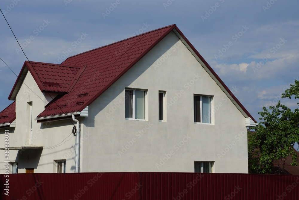white private house with a window under a red tiled roof against a sky on a sunny day white private house with a window under a red tiled roof against a sky on a sunny day