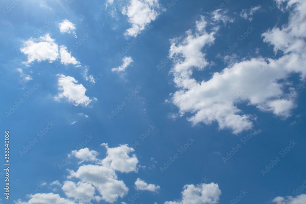 Beautiful sunny blue sky background with puffy fluffy white clouds & cotton candy cumulus cloudscape on tropical summer horizon in bright sunlight & sun ray at daylight sunshine day, copy free space Beautiful sunny blue sky background with puffy fluffy white clouds & cotton candy cumulus cloudscape on tropical summer horizon in bright sunlight & sun ray at daylight sunshine day, copy free space