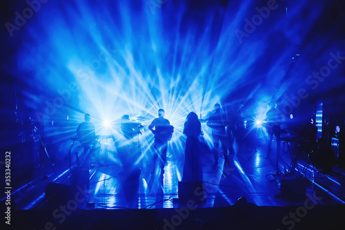 silhouettes of musicians on stage in the rays of light