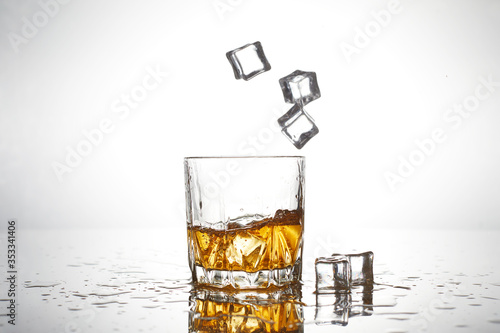 glass of whiskey with drop ice cube on white background isolated