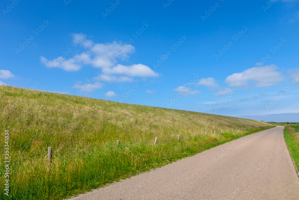 Small road running along a high dike protecting the land from the sea Small road running along a high dike protecting the land from the sea