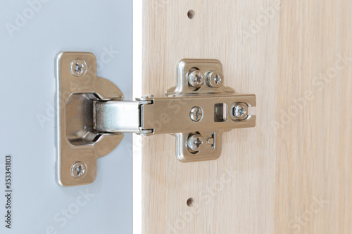 Polished Stainless door hinge on a cabinet door for interior design.