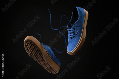 Vászonkép Close up view of levitation blue sneakers shoes with  flying laces over black background with copy space for text