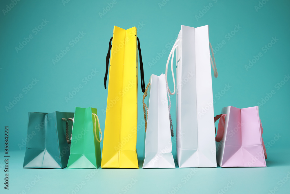 Many different colorful empty paper bags isolated on aquamarine background