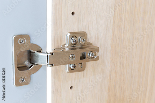 Polished Stainless door hinge on a cabinet door for interior design.