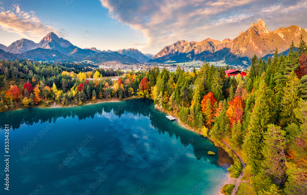 Fototapeta premium View from flying drone. Majestic morning scene of Urisee lake. Fabulous autumn view of Reutte town, Austria, Europe. Fantastic sunrise in Austrian Alps. Traveling concept background.