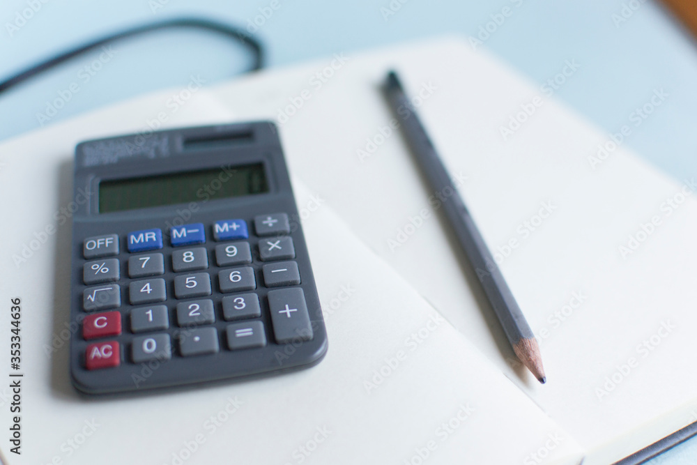 The calculator on the table. Small accountant calculator on the background of a notebook. Calculations, records, business analytics. The calculator on the table. Small accountant calculator on the background of a notebook. Calculations, records, business analytics.