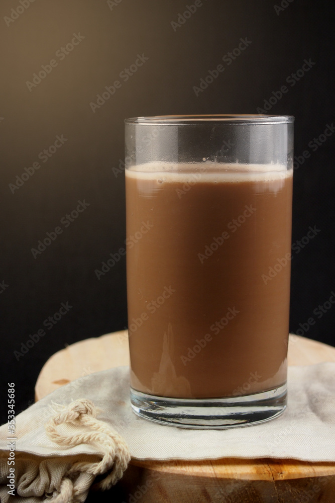 Serve a glass of warm chocolate milk on a tray. Serve a glass of warm chocolate milk on a tray.