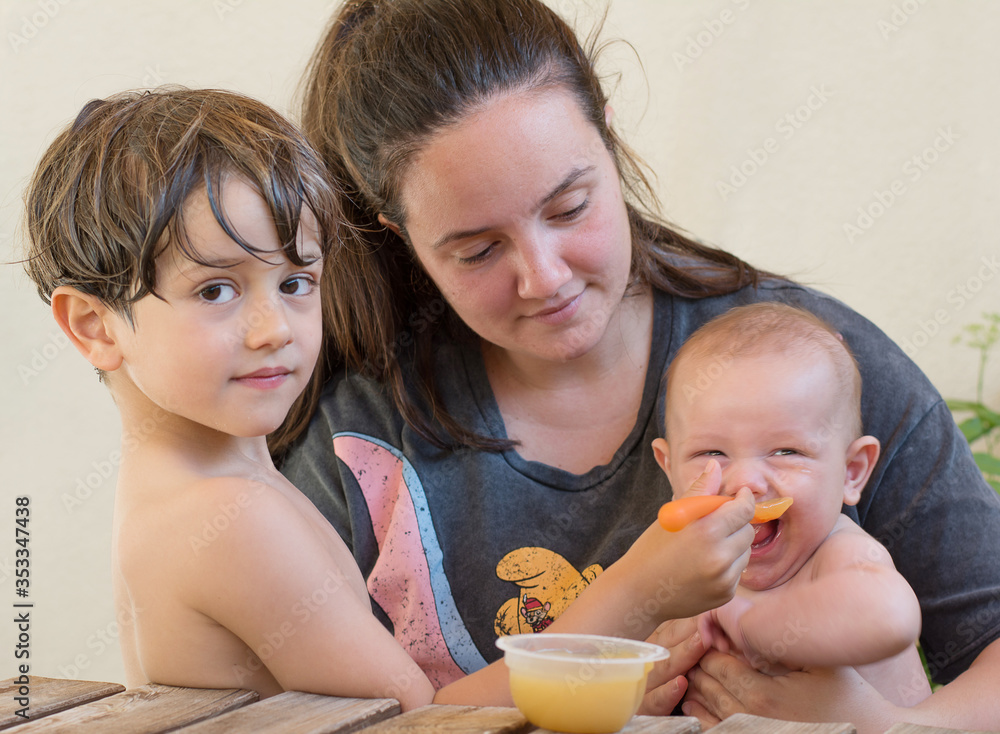 New families. Woman with her two young children feeding them. Happy Lifestyle New families. Woman with her two young children feeding them. Happy Lifestyle