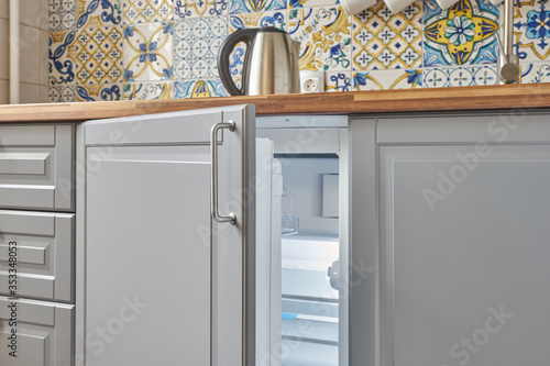 Fotografi compact built-in refrigerator under the countertop in the kitchen