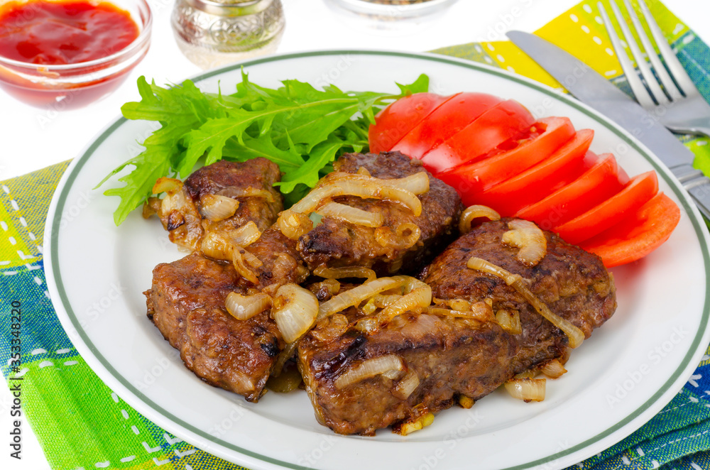 Pieces of fried liver with onions, fresh leaves of salads