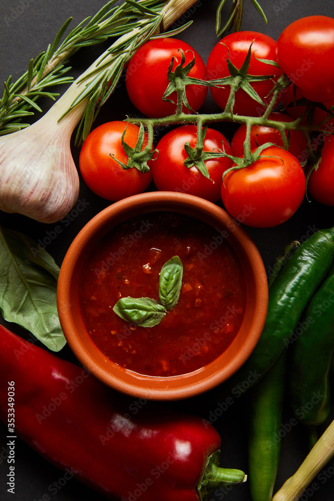 top view of ripe cherry tomatoes, garlic, tomato sauce in bowl and rosemary near chili peppers top view of ripe cherry tomatoes, garlic, tomato sauce in bowl and rosemary near chili peppers
