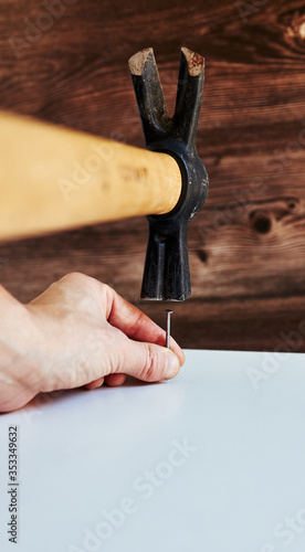 Closeup of hands driving a nail into wood. Unrecognized person. Only hands