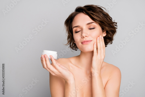 Closeup photo of beautiful attractive lady short bob hairdo hold new daily night treatment cream jar apply cheekbone eyes closed pleasant effect isolated grey color background