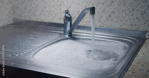 Overflowing kitchen sink with water and foam blockage sin