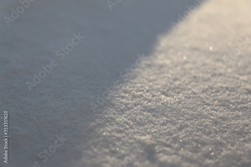 Close up of white snow, with sunlight taking one half and the shadow taking up the other half. 