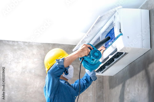 Technician man repairing ,cleaning and maintenance Air conditioner on the wall with blower in bedroom or office room.On site home service,Business ,Industrial concept.