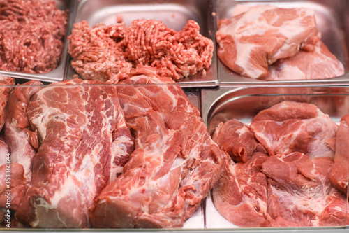 Heap of fresh meat food meat food background in supermarket store. Different types of raw meat in plastic boxes, leg of lamb on the bone, beef tail, beef neck, beef blade. Concept of farm and raw