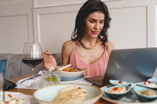 Beautiful young woman using laptop in restaurant