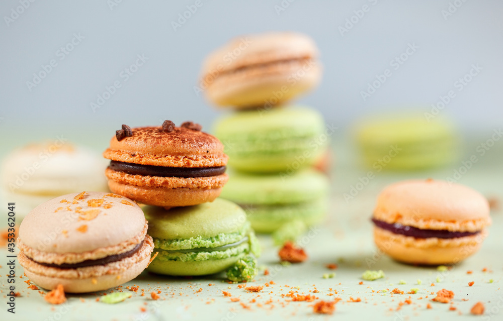 Colorful background with delicious french green and orange macaroons

